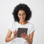 Mulher com óculos de descanso sorrindo enquanto segura e lê em tablet em fundo branco