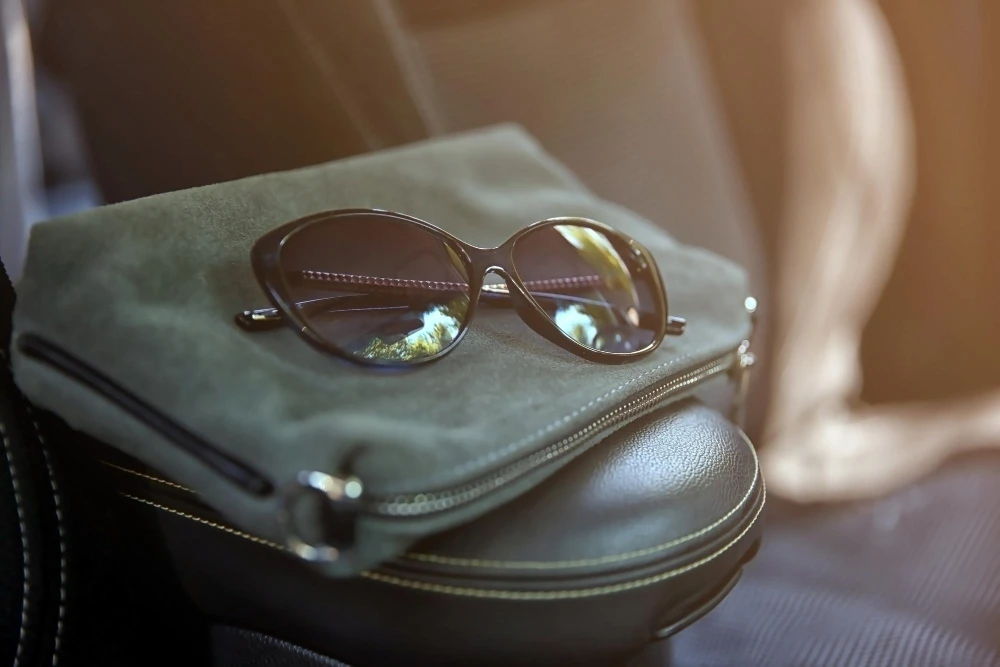 Óculos burberry original em cima de bolsa verde em carro