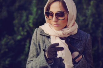 mulher com óculos de inverno usando agasalhos, lenço e luvas