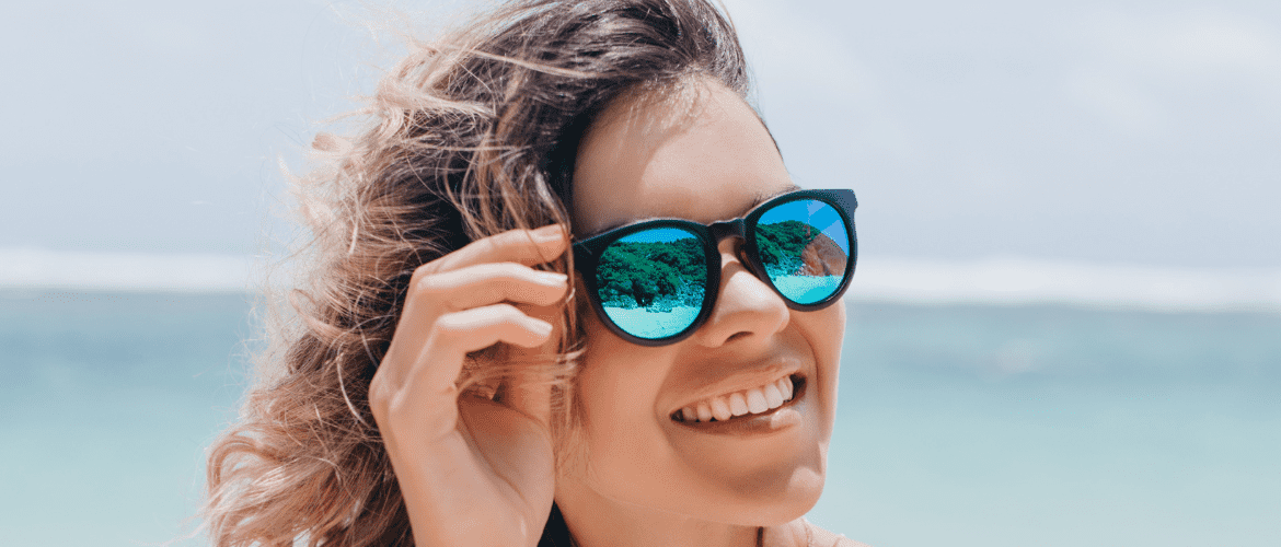 mulher com roupas de banmho usando óculos de sol para praia