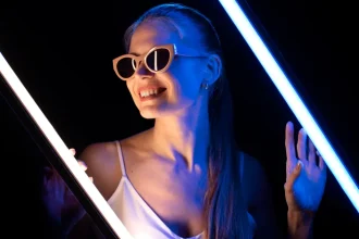 Mulher com óculos de festa de luxo em fundo preto iluminada com luz neon azul