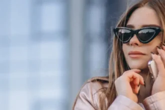 mulher branca falando ao telefone quanto usa um óculos escuro de luxo