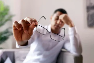 Homem com dor de cabeça segurando óculos