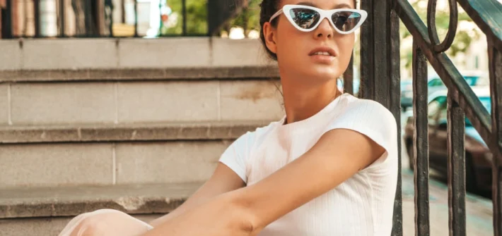 Mulher sentada em escada usando óculos de sol fazendo pose