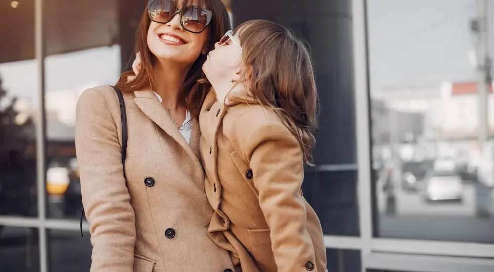 Mãe e filha usando casacos sobretudo e óculos de sol escuro combinando.