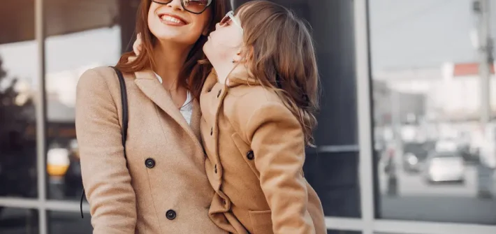 Mãe e filha usando casacos sobretudo e óculos de sol escuro combinando.