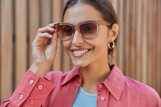 Mulher sorrindo segurando com uma mão com óculos statement no rosto