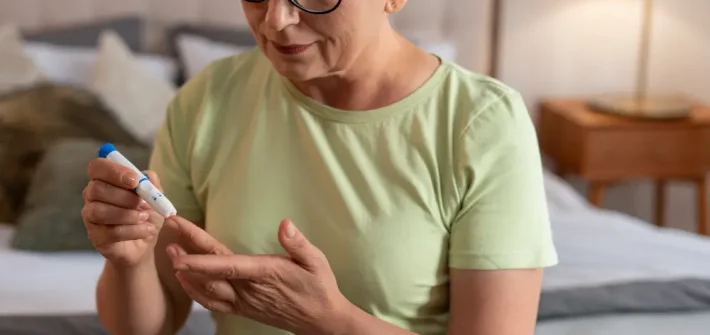 Mulher idosa de óculos com diabete colendo sangue para medir nível de glicose no sangue