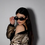 Mulher com óculos e maquiagem olhando para a câmera de lado