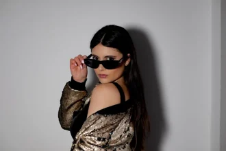 Mulher com óculos e maquiagem olhando para a câmera de lado