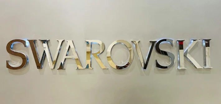 Placa com nome da loja de óculos Swarovski em material espelhado