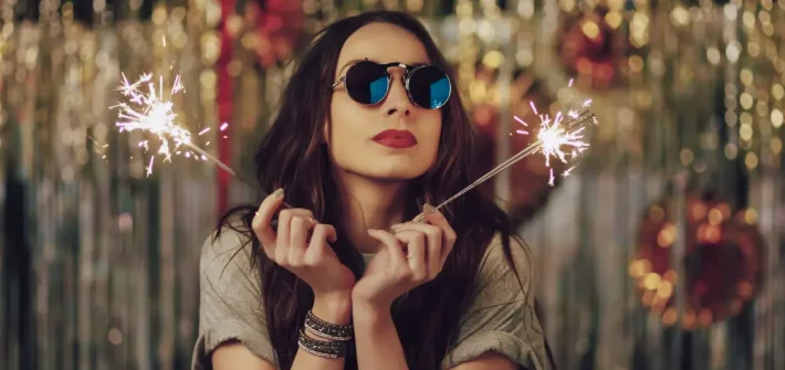 Mulher com óculos escuro no ano novo segurando vela faísca
