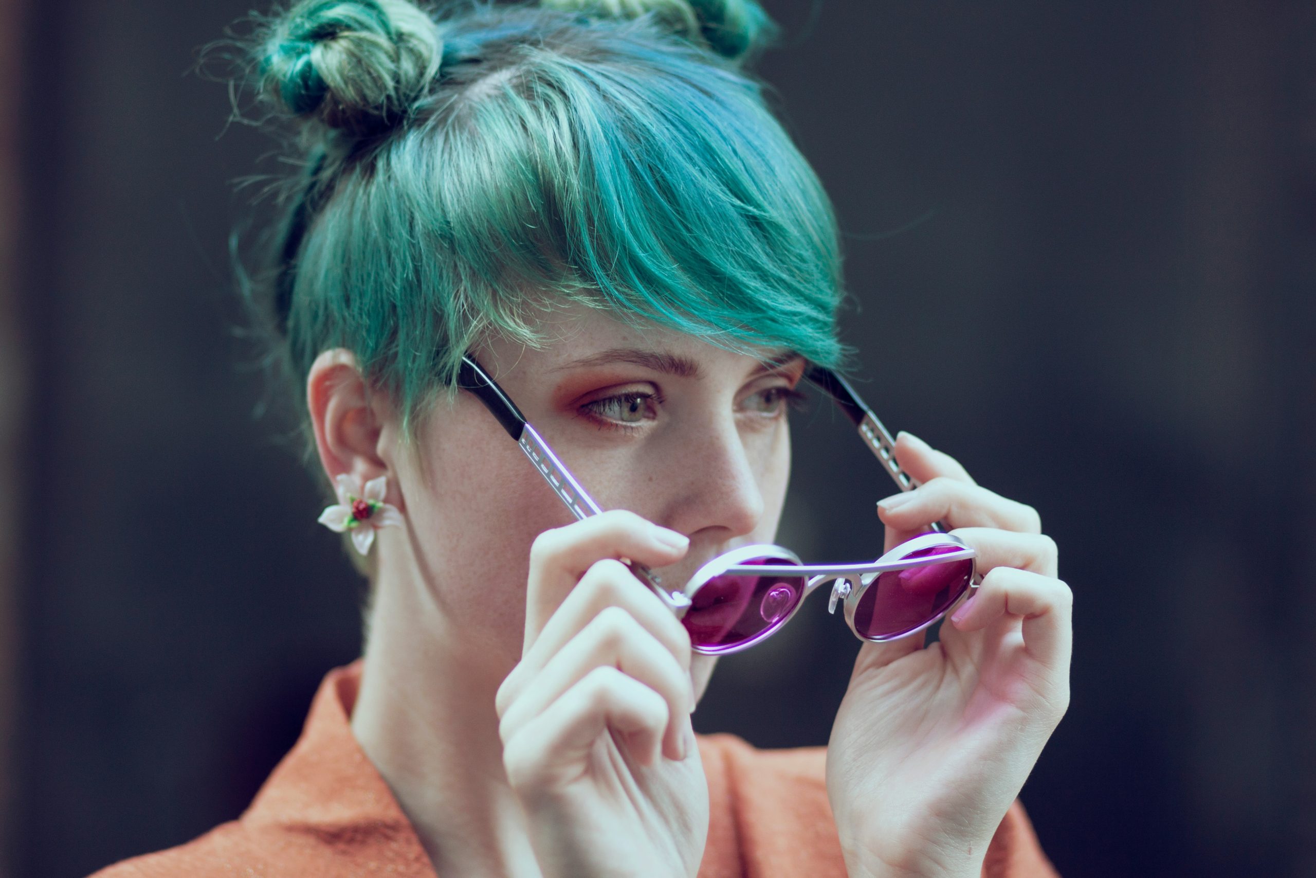 mulher de cabelo azul colocando um oculos que combina com a sua personalidade