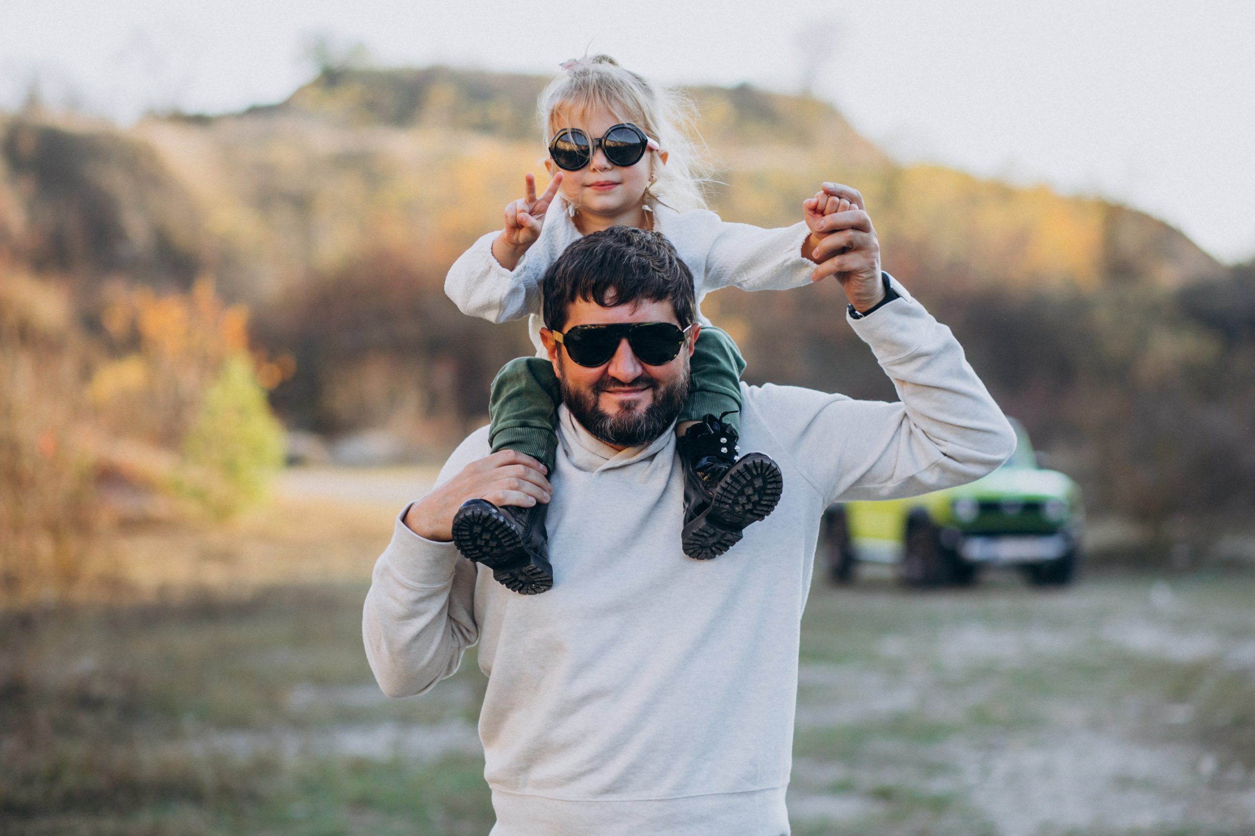 pai com sua filha nos ombros usando oculos de sol